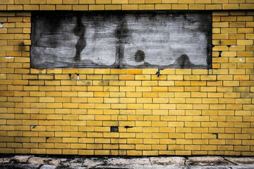 Yellow brick walls are dirty old age and have cement on top.