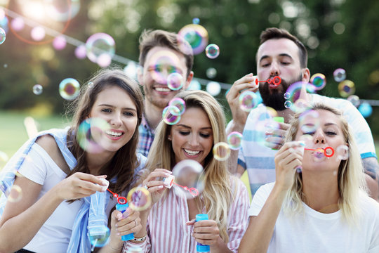 Happy Group Of Friends Blowing Bubbles Outdoors