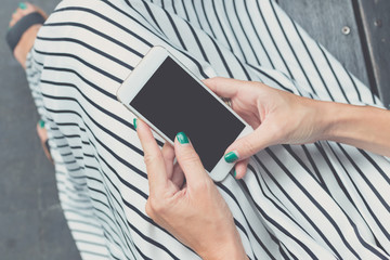 Woman hands using smartphone on a bench background in the park. Bali island, Indonesia.