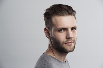 Close up portrait of serious gloomy bearded man with stylish hairstyle posing against white background. Handsome guy with blue eyes frowning his face showing his disatisfaction and dipleasment
