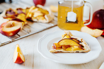 Sweets, desserts and pastries, French cuisine, biscuits, galette with peaches, fresh fruits, milk and green tea on a light background 