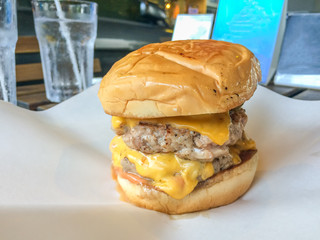 Cheese burger with pork, melted cheese, vegetable, on white paper, closeup shot