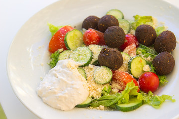 Chickpea falafel balls with vegetables In a white plate on table. Middle Eastern food.