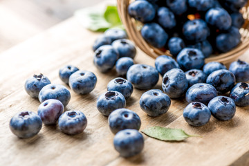 Freshly blueberries on wooden rustic wooden table. Juicy and fresh blueberries with green leaves. Bilberry on wooden background. Blueberry antioxidant. Concept for healthy eating and nutrition.
