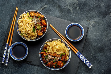 Chicken teriyaki on dark background with balsamic sauce and sesame seeds. Asian food. Noodles, chicken and soy sauce. Top view.
