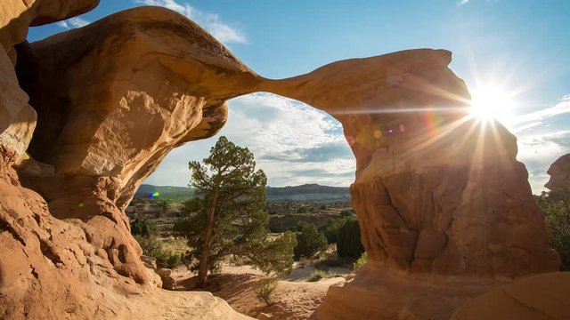 Sun rays shining in time lapse of Meta Arch in the Escalante Utah desert.