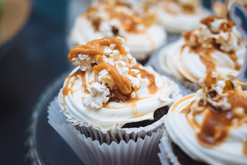 Homemade cupcakes with caramel syrup and fresh cream topping. Candy bar for birthday patry...