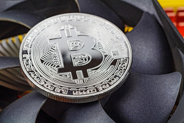Silver bitcoin on the central processing unit fan background closeup. Cryptocurrency virtual money