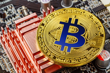Golden bitcoin on the computer motherboard background closeup. Cryptocurrency virtual money