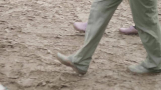 Legs of people in rubber boots walking in mud after rain. Slow motion