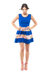 Cute woman in  blue summer dress looking down with windy flying hair.  Full body length portrait isolated on white studio background.