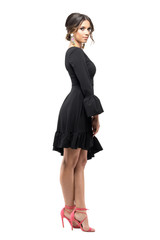 Fototapeta premium Seductive sensual Latin woman in black dress posing and looking at camera. Full body length portrait isolated on white studio background.