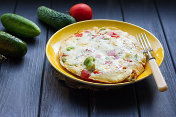 omelette from chicken eggs with cheese, fresh vegetables - cucumber and tomato