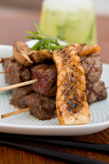 Delicious beef steak cuts on a wooden skewer, cooked rare, served with perfectly grilled mushrooms.