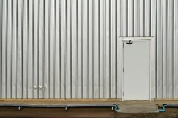 white door in old and dirty metal wall  on dirty concrete for background 