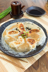 Chicken Gyoza, japanese pan fried dumplings served on a rustic plate.