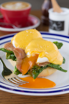 Eggs benedict and fresh salmon serves on a lightly toasted muffin served with hollandaise sauce and a coffee.