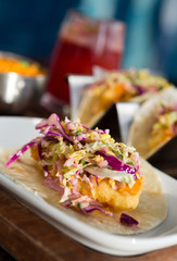 Mexican fried cod fish taco served with lettuce, red onion and sauce