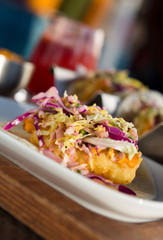 Mexican fried cod fish taco served with lettuce, red onion and sauce