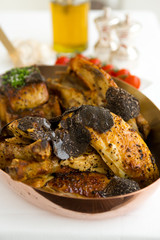 Roasted chicken with foie gras and truffle sauce, topped with sliced truffle, served in a metal pan.