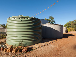 Large green rainwater collection tank and concrete tank, on a farm in Australia