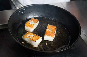 Pan fried golden fish fillet cubes, frying in real butter, in a non stick rustic pan.