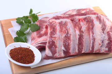 Raw pork ribs with herbs and spices on wooden board. Ready for cooking.