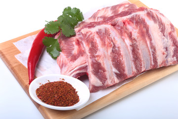 Raw pork ribs with herbs and spices on wooden board. Ready for cooking.