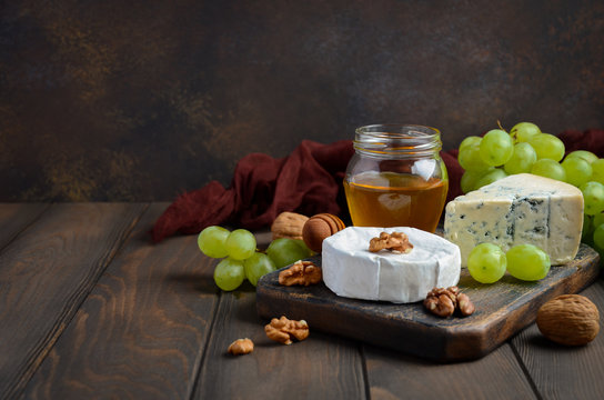 Variety of cheese with grapes, walnuts and honey. Selective focus, copy space.