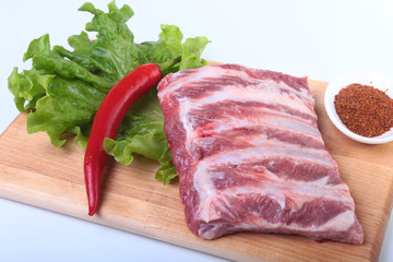 Raw pork ribs with herbs and spices on wooden board. Ready for cooking.