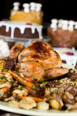 Unique beautiful christmas meal platter, with roast chicken and vegetables, surrounded by cakes, mince pies, fruit, bread and jam.