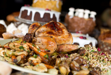 Unique beautiful christmas meal platter, with roast chicken and vegetables, surrounded by cakes,...
