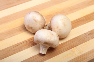 Fresh white mushrooms champignon on wooden background.