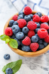 Wooden bowl with raspberries and blueberries.