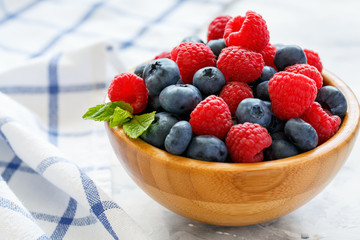 Fresh raspberries and blueberries in wooden bowl.