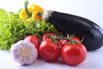 Fresh assorted vegetables, eggplant, bell pepper, tomato, garlic with leaf lettuce. Isolated on white background. Selective focus.