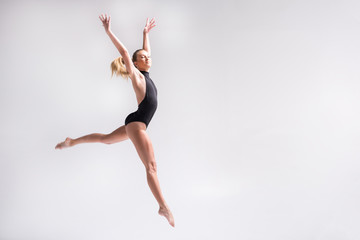 Fototapeta na wymiar Sublime youthful lady performing gymnastics choreography jump