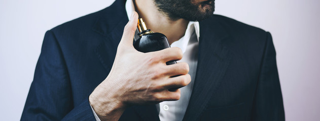Handsome young businessman using perfume