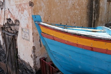 Fototapeta na wymiar Madeira, Portugal: Alte Häuserfassade und Holzboot an der Küste von Madeira.