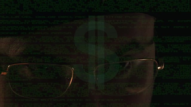 A hacker in a dark room reflected in the monitor 