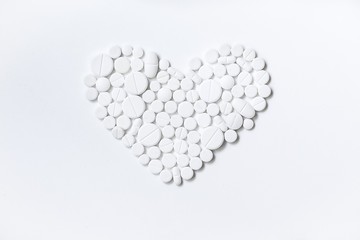 Heart of white pills on a white background