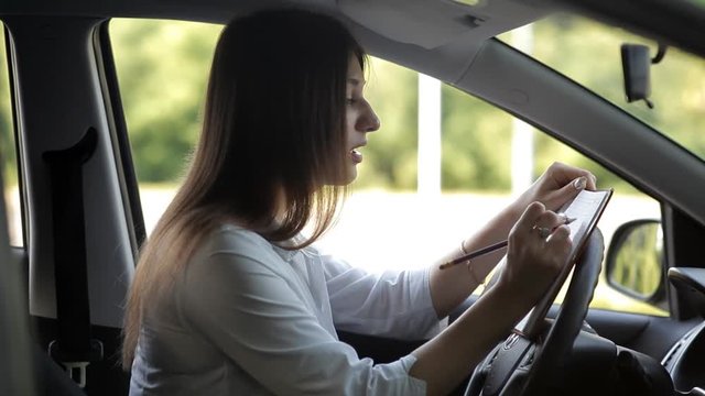 Business girl, while in the car, records in a notebook for work