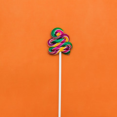Colorful lollipop Flat lay Minimal concept Multicolored lollipop on an orange background One spiral candy on a stick Trendy style photo Top view