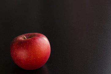 One red apple on black background