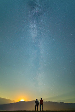 The two men stand on the background of the milky way. night time