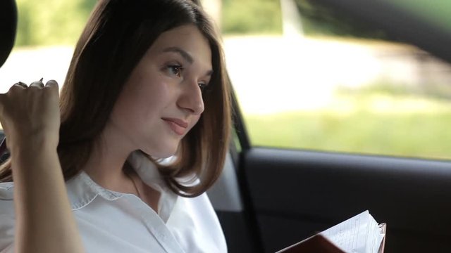 Business girl, while in the car, records in a notebook for work