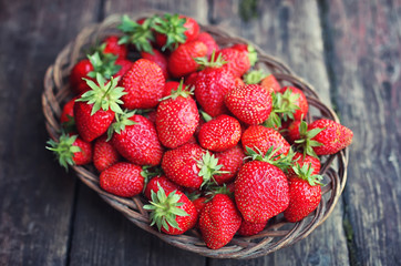 Strawberry in wicker plate on wooden background
