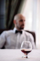 A glass of cognac on a background of men.