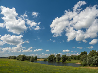 small lake surrounded by trees and green meadows on a stormy afternoon