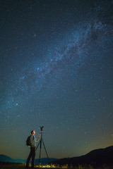 Fototapeta na wymiar The man with a camera stand on the milky way background. night time